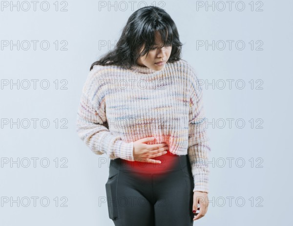 Sore Asian woman with digestive problems. Female person holding stomach with digestive problems isolated