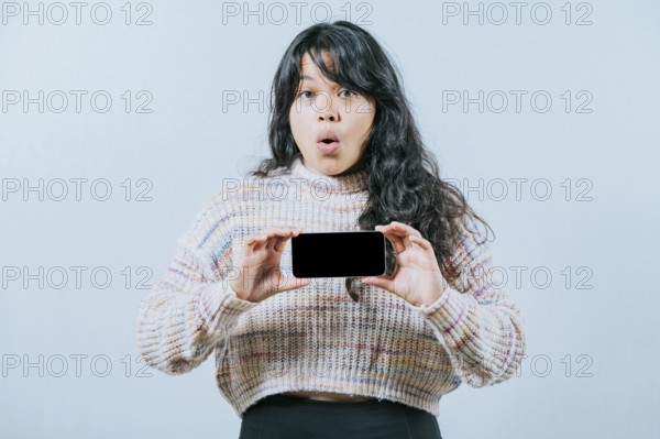 Surprised asian woman showing phone screen isolated. Beautiful asian girl showing promotion on screen phone
