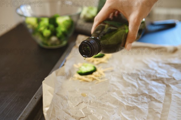 Broccoli florets and cheese are being prepared in a kitchen. Olive oil is drizzled on parchment to enhance flavour. This scene shows the process of making a simple dish at home