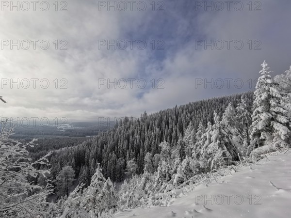 Snowy landscape with wooded mountain and clouds in the sky, idyllic winter atmosphere, Rennsteig, Thuringian Forest