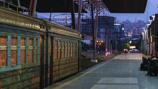 Illuminated train station with old train and city scenery at dusk, Yerevan, Armenia