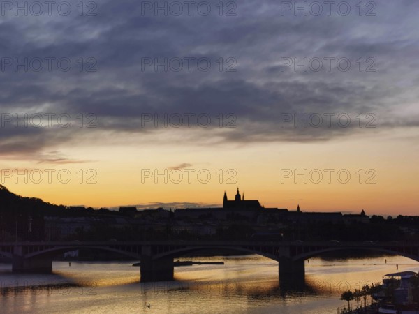 Dusk over a city with a bridge, river and silhouette of buildings in the background, Prague, Czech Republic