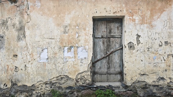 Abandoned wall with old wooden door and rough texture, Georgia