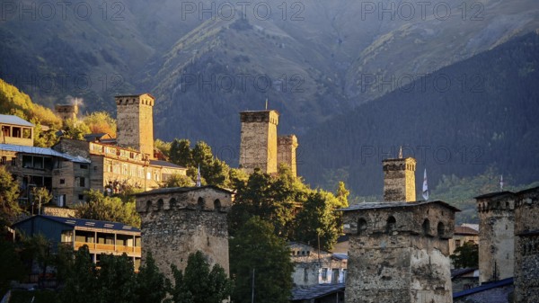 Village with historic towers and mountains in the background at sunset, Mestia, Georgia