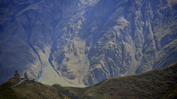 Picturesque mountain slopes with church on a hill in daylight, Gergeti Monastery, Georgia