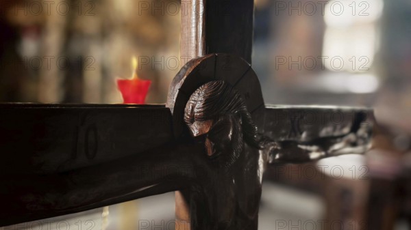 Detail of a wooden cross with a burning candle in the background in an atmospheric light, North Macedonia