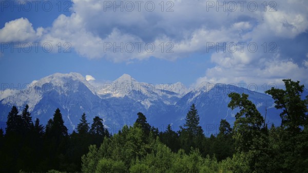 Mountain panorama with wooded foreground and blue sky full of clouds, Slovenia