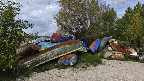 Abandoned, colorful boats are piled up in a natural environment, North Macedonia