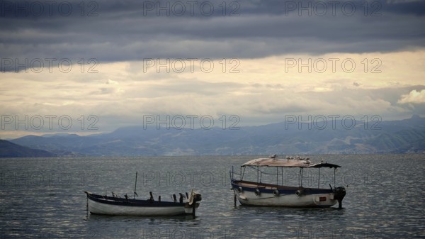 Two small boats float on a calm lake under a dramatic sky, Lake Ohrid, North Macedonia