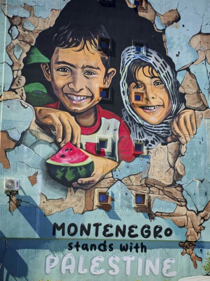 Wall painting of laughing children with text in support of Palestine