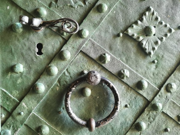 Old green door section with decorative handle and metal ornaments