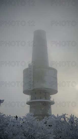 Mighty tower, surrounded by snow and fog, towering into the cloudy sky, Baköfele on the Schneeberg, Fichtelgebirge, Bavaria