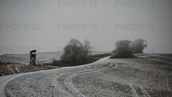 Cold winter day with a snowy dirt road and raised chair, Franconian Forest nature park Park