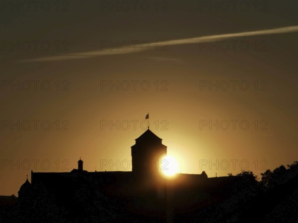Castle silhouette in front of a sunset with golden sun on the horizon