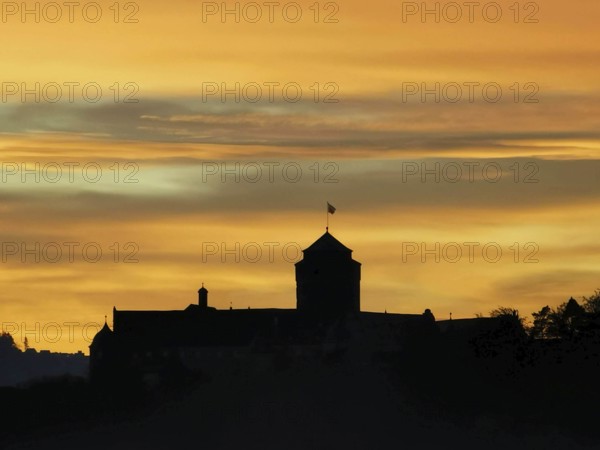 Silhouette of a castle against an orange sky at sunset