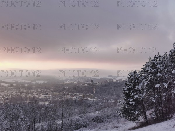 Snowy hills with a view of a village at sunset, view of Rosenberg Fortress and the town of Kronach, Upper Franconia