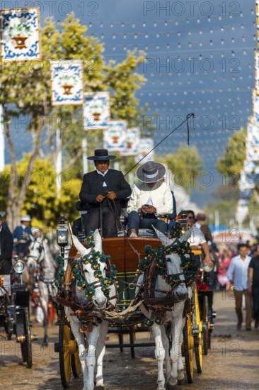 Seville, Spain, Europe. Men in traditional equestrian clothes driving a horse drawn carriage during the Feria de Abril