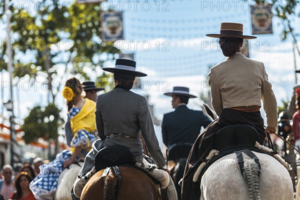 Seville, Spain, Europe. Young women and men in traditional equestrian clothes on horseback during the Feria de Abril