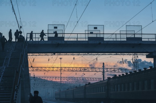 Siberia, Russia. People crossing a bridge at the train station near the Trans Siberian railway on its way to Moscow at dawn