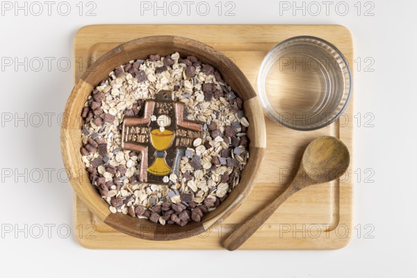 Wooden bowl with cereal and a cross on a wooden board with water, fasting