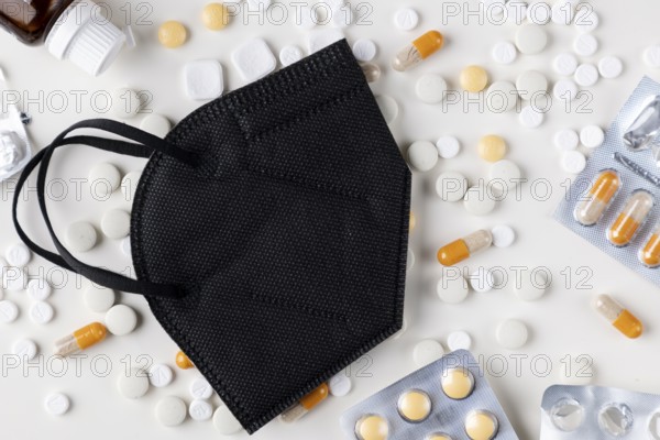 Black respirator on a table with scattered tablets and capsules