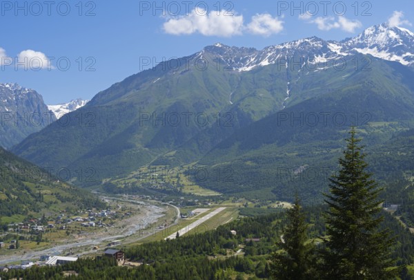 Valley with river and adjacent mountains under a bright blue sky, in the middle an airport, Mestia, Mingrelia and Upper Svaneti, Svaneti, High Caucasus, Georgia