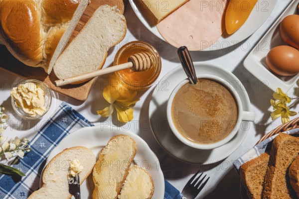 Breakfast, stollen with butter and honey, surrounded by cheese, ham, coffee, peppers and eggs