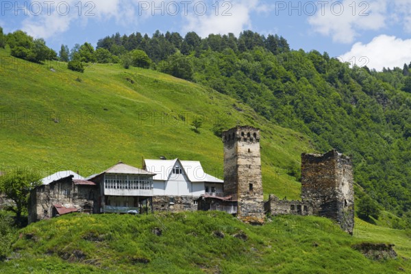 Medieval village with tower on a hill in the background, surrounded by green landscape and clear sky, Davberi, Mingrelia and Upper Svaneti, Svaneti, High Caucasus, Georgia