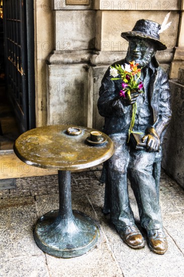 Life-size bronze sculpture as a memorial to Piotr Skrzynecki, Polish choreographer and cabaret director sitting at a coffee table, rynek with cloth halls, from 13th century, main market, city landmark, Krakow, Poland