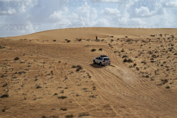 Car drives over sandy road, Wahiba Sands desert, Oman