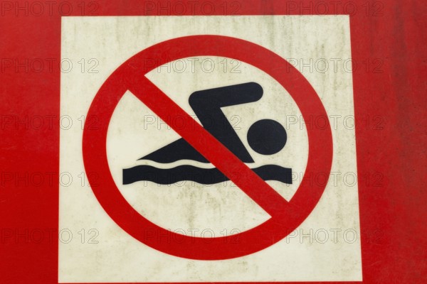 Close-up of posted painted red and white with illustrated swimmer in solid black on metal pictogram sign warning of Swimming Prohibited or Not Allowed, Quebec, Canada