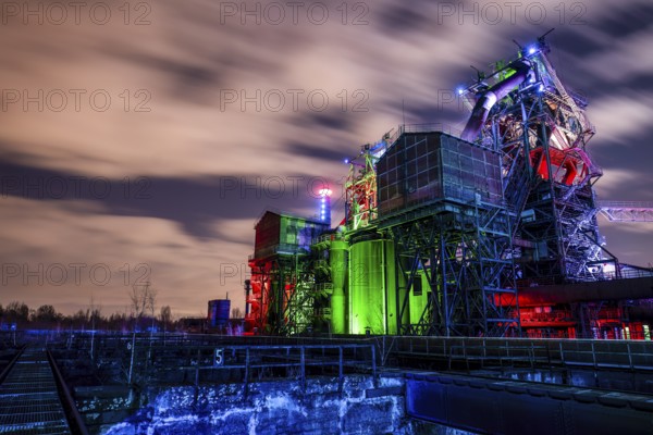 Industrial complex at dusk with colorful lighting and moving cloudy sky, Duisburg Nord Landscape Park, Duisburg, North Rhine-Westphalia, Germany