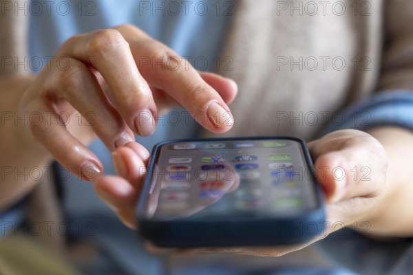 Mobile phone, in a user's hand, screen with various apps