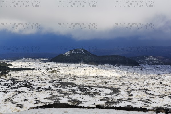 Wide, rugged lava field with volcanic cones, snow debris, curved road, Etna, Etna, Catania, Sicily, Italy