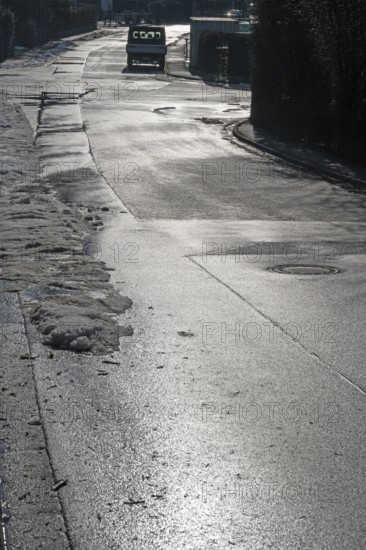 Remains of snow on rain-wet road against light, Eckental, Middle Franconia, Bavaria, Germany