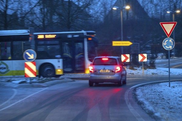 Car and bus at roundabout during night snow flurries, Eckental, Middle Franconia, Bavaria, Germany
