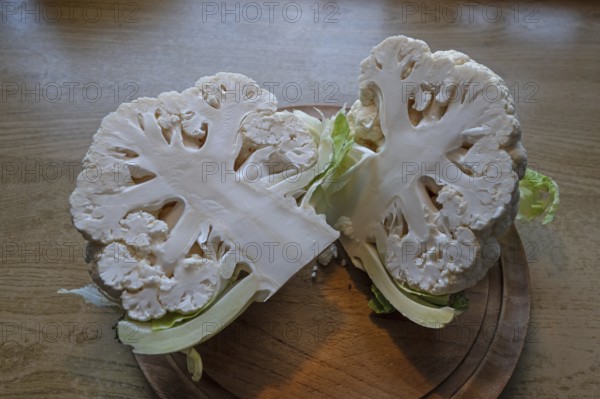 Halved cauliflower (Brassica oleracea var. botrytis) on a wooden board, Bavaria, Germany