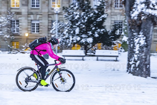 Winter in Stuttgart. It snowed overnight and the city is wintry white early in the morning. Cyclists in the snow in the Lower Palace Garden. Stuttgart, Baden-Württemberg, Germany