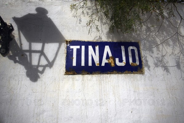 Blue sign with the words' Tinajo 'on a white wall shaded by a lantern, Tinajo Lanzarote