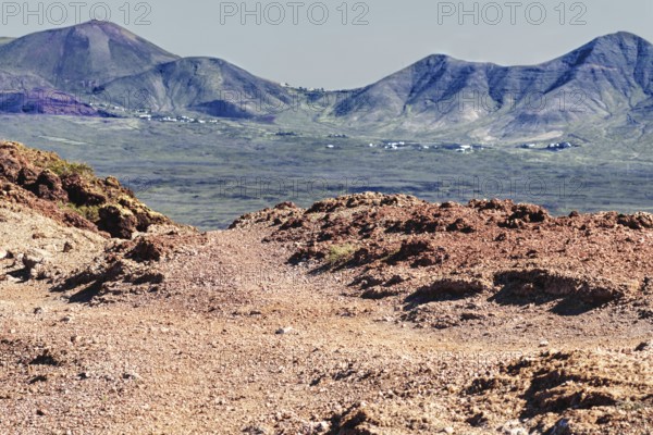 Volcanic mountain landscape with red earth formations and distant mountains, Playa Blanca Lanzarote