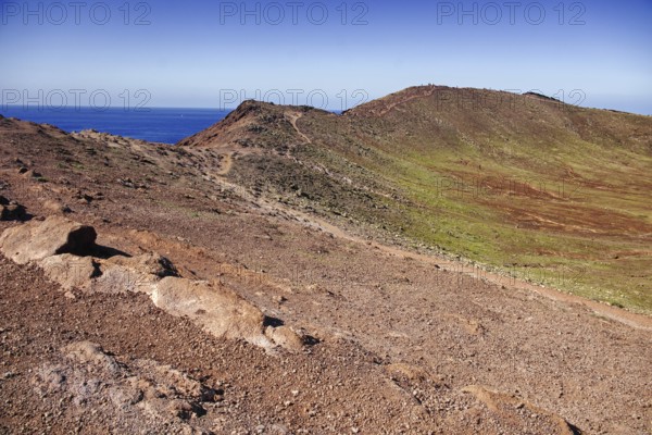 Barren volcanic landscape with ocean views under clear skies, Playa Blanca