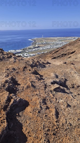 View from a rocky volcanic mountain (Montana Roja) to the distance and the blue sea, Playa Blanca Lanzarote