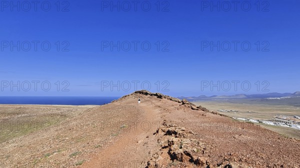 Narrow path on the summit of the Montana Roja volcano with views of the sea under a clear blue sky, Playa Blanca Lanzarote