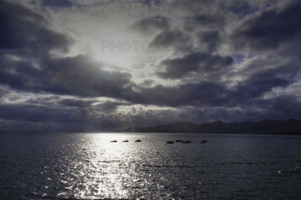 Dramatic atmosphere over the sea, clouds obscuring the sun, reflecting light on the water, Puerto del Carmen Lanzarote