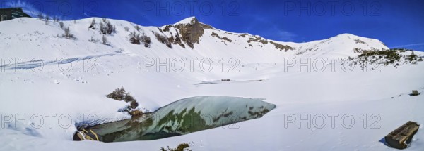 Alpine mountain panorama in snow on Schlappoldsee with wooden bench on Fellhorn in spring in the Allgäu Alps in the sun with blue sky, Allgäu, Alps, Bavaria, Germany