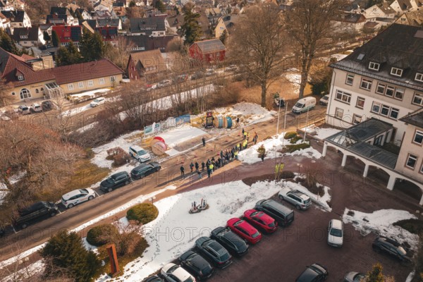 Aerial view of a people meeting on a snow-covered street and parking lot, fiberglass groundbreaking, Freudenstadt, Germany