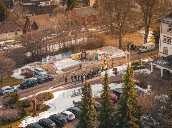 Aerial view of a crowd of people next to cable drums on a snowy road, fiberglass groundbreaking, Freudenstadt, Germany