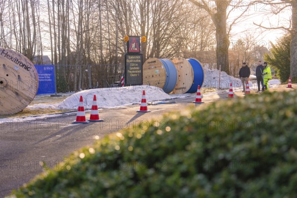 Cable rolls and traffic cones on a road in a sunny winter landscape, fiberglass groundbreaking, Freudenstadt, Germany