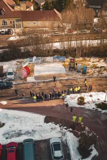 Gathering of people on a snowy road, watched from the air, fiberglass groundbreaking, Freudenstadt, Germany