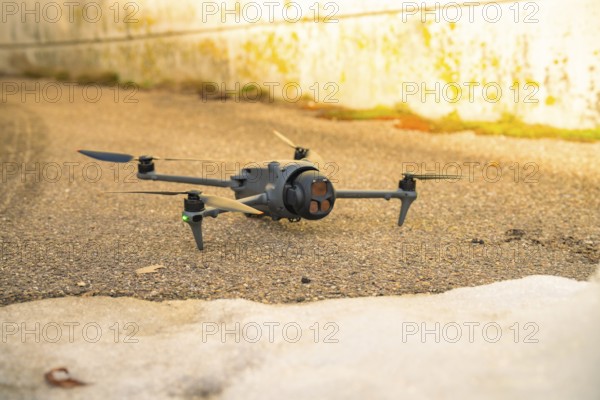 A black drone is lying on an asphalt path for outdoor use, fiberglass groundbreaking, Freudenstadt, Germany